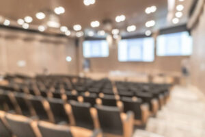 Seminar conference or town hall meeting blur background in auditorium or hotel room with audiences, speaker podium stage and presentation screen for entrepreneurship business speech or community talk