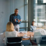 Businessman, meeting and discussion with office, boardroom and collaboration or workshop. Leader, training and presentation for mentor, coaching and strategy for teamwork and planning with startup